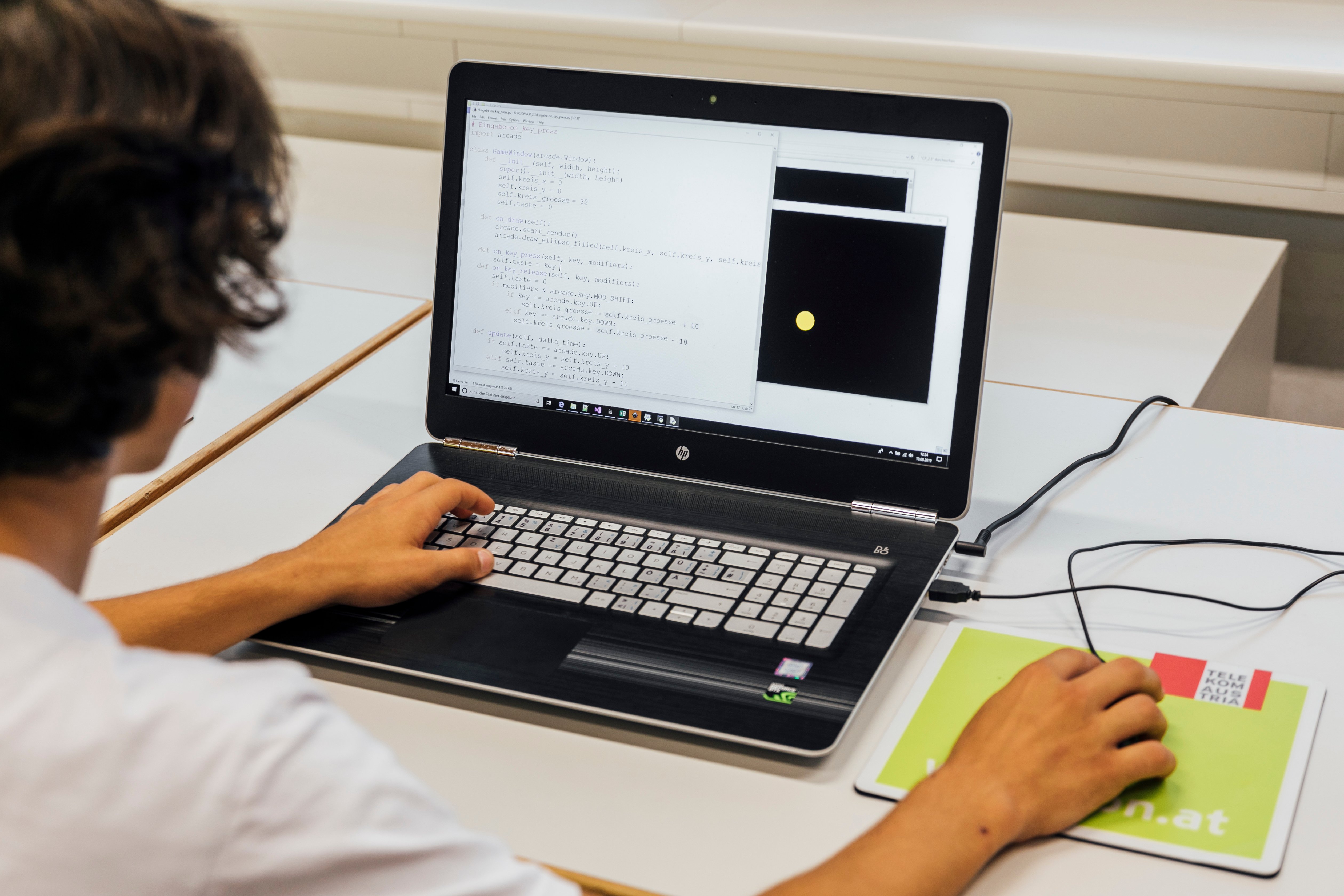 Junge 15 sitzt am Bildschirm und programmiert Python