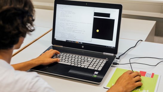 Junge 15 sitzt am Bildschirm und programmiert Python